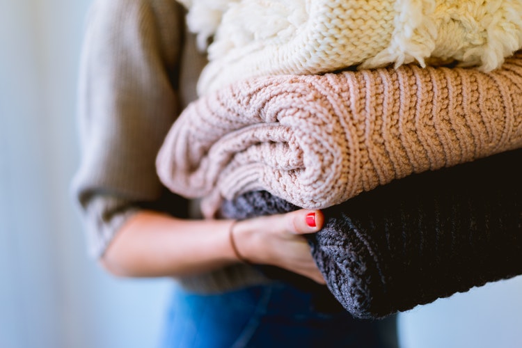 јесенске идеје за инстаграм - девојка са савијеним џемперима у рукама